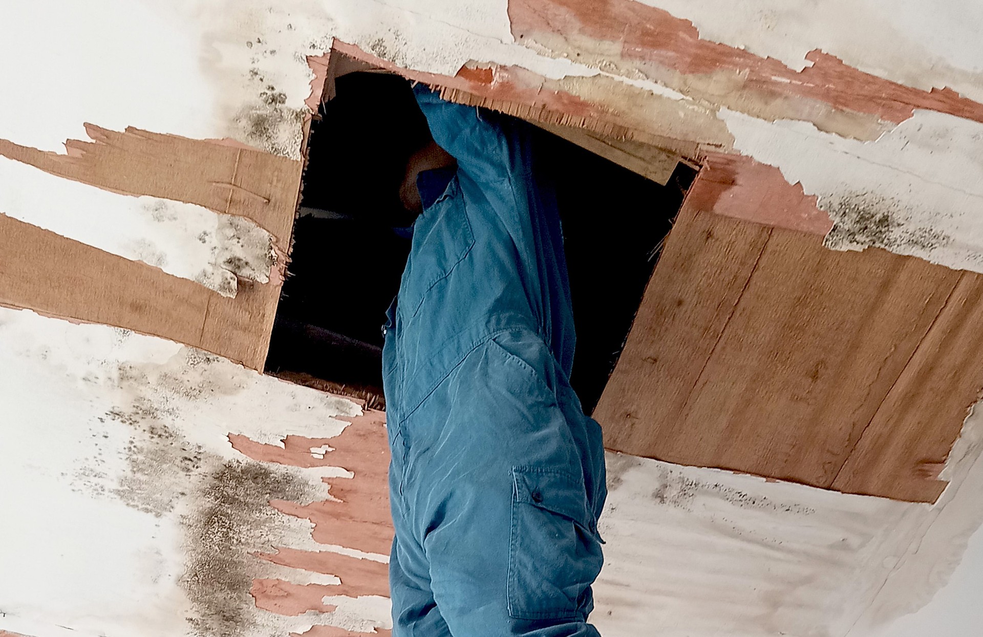 A man repairs the leaking ceiling.